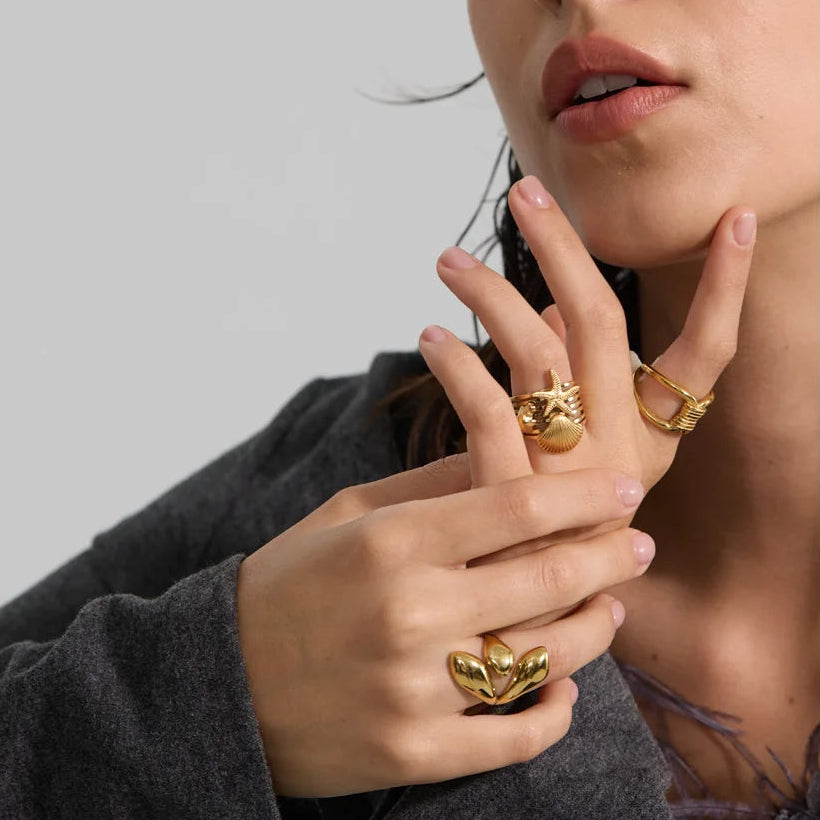 Woman wearing gold rings on a plain background