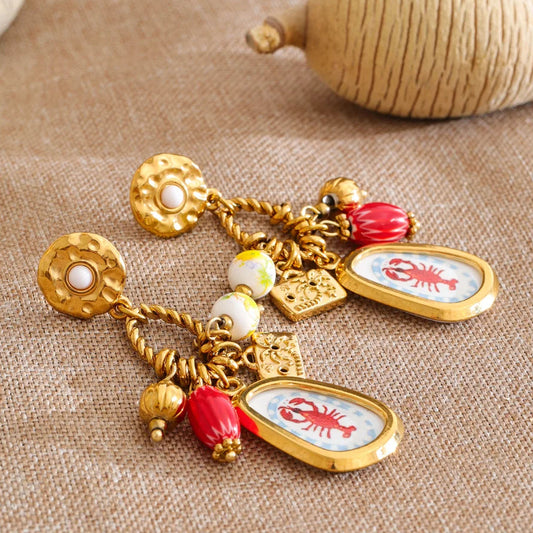 Gold charm bracelet with lobster charms on a textured fabric background