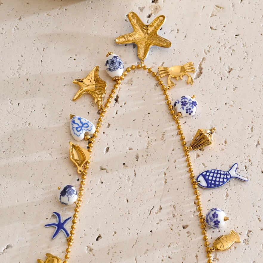 Necklace with starfish, fish, and shell-shaped pendants on a textured beige surface