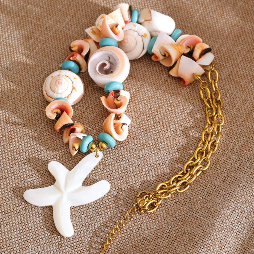 Bracelet with shell beads and a gold chain on a textured surface