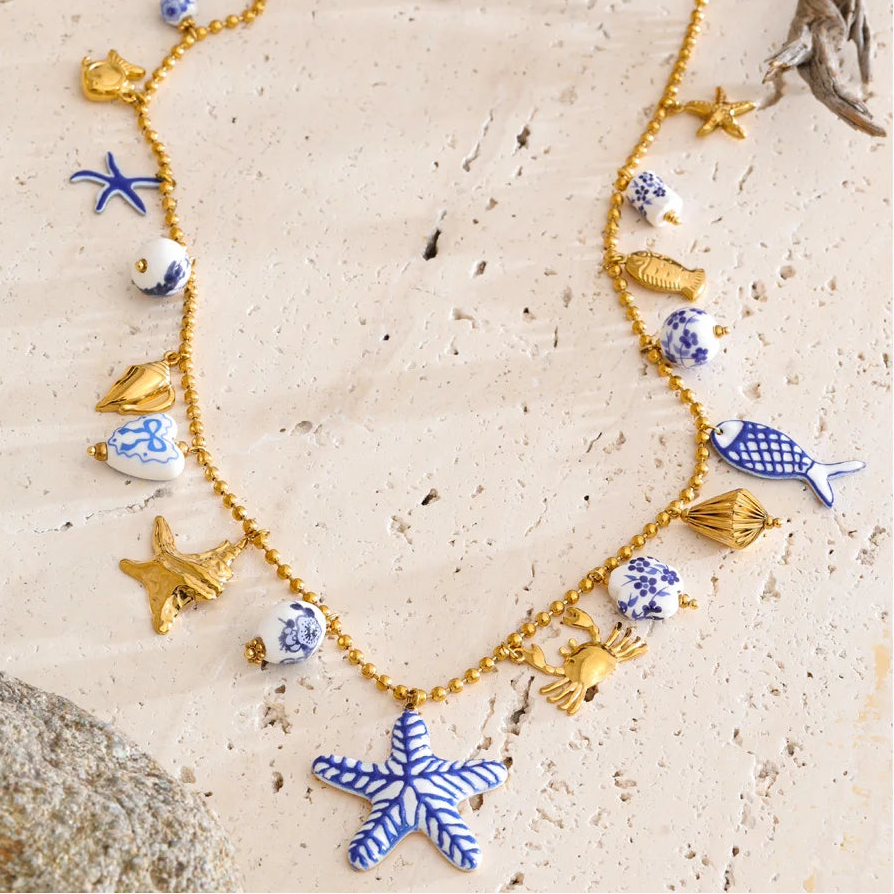 Necklace with blue and gold sea-themed charms on a sandy background