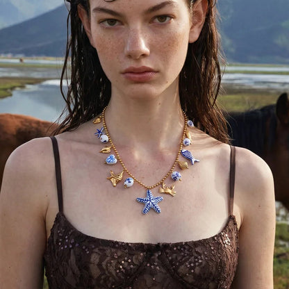 Woman wearing a necklace with starfish pendants in a natural setting with horses and mountains.