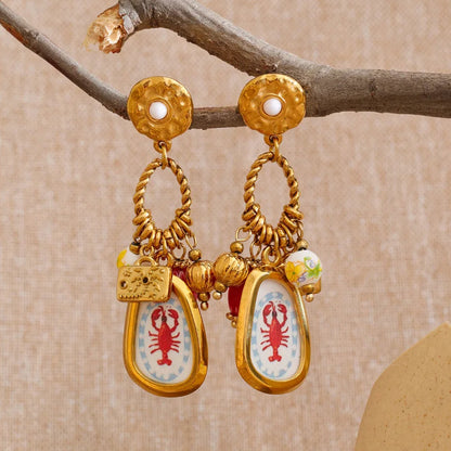 Gold earrings with lobster designs on a beige background
